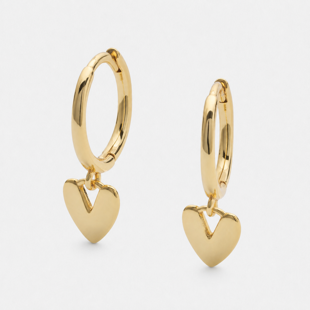 Heart drop hoop earrings in a gold finish on a neutral off-white background.