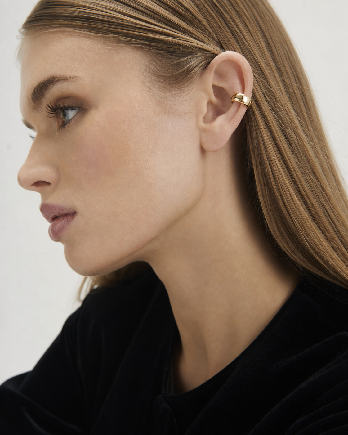 Profile showing a gold-coloured ear cuff fitted around the outer ear cartilage