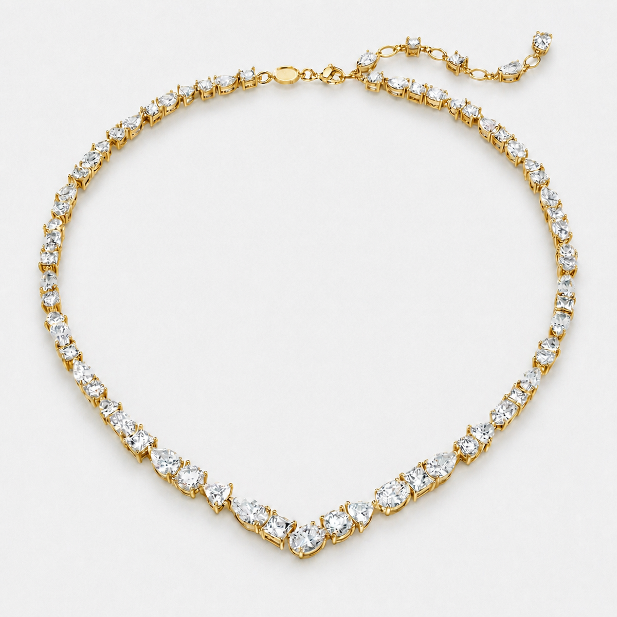 Graduated mixed-cut clear crystal V necklace in a gold finish on a neutral off-white background.
