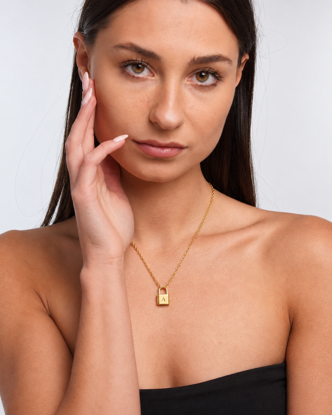 Padlock pendant necklace engraved with initial A in a gold finish worn by the model.
