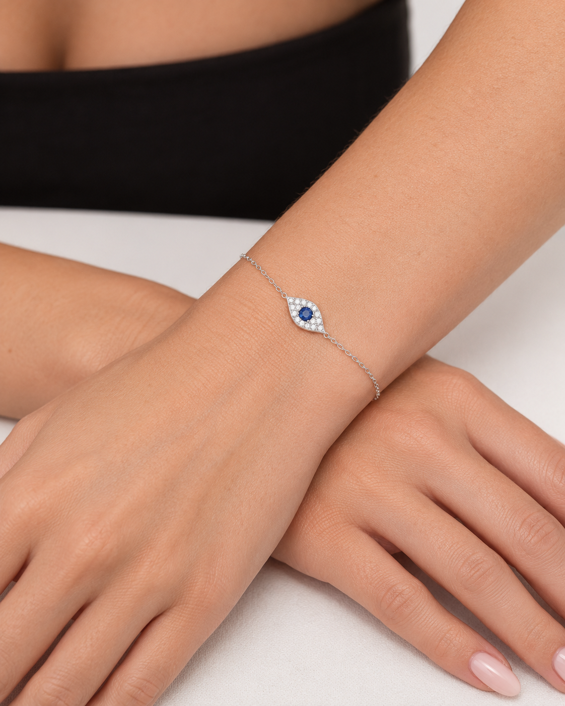 Pavé evil eye chain bracelet in sterling silver with a blue centre stone, worn in close-up on the wrist