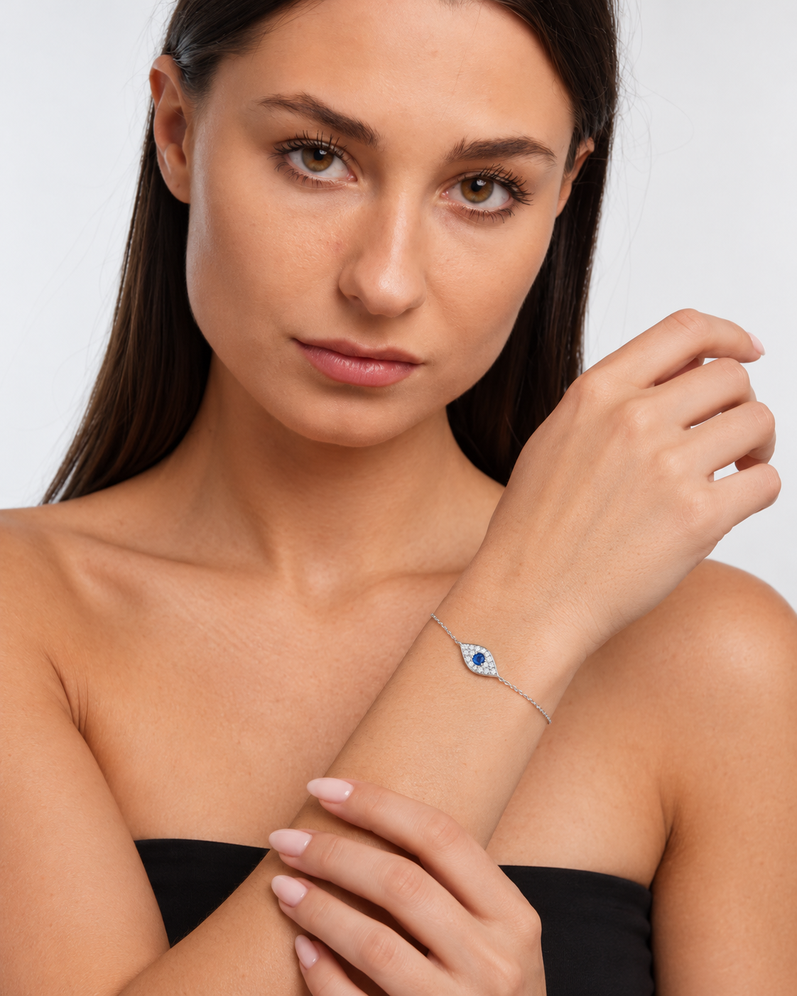 Pavé evil eye chain bracelet in sterling silver with a blue centre stone, worn in supported wrist pose