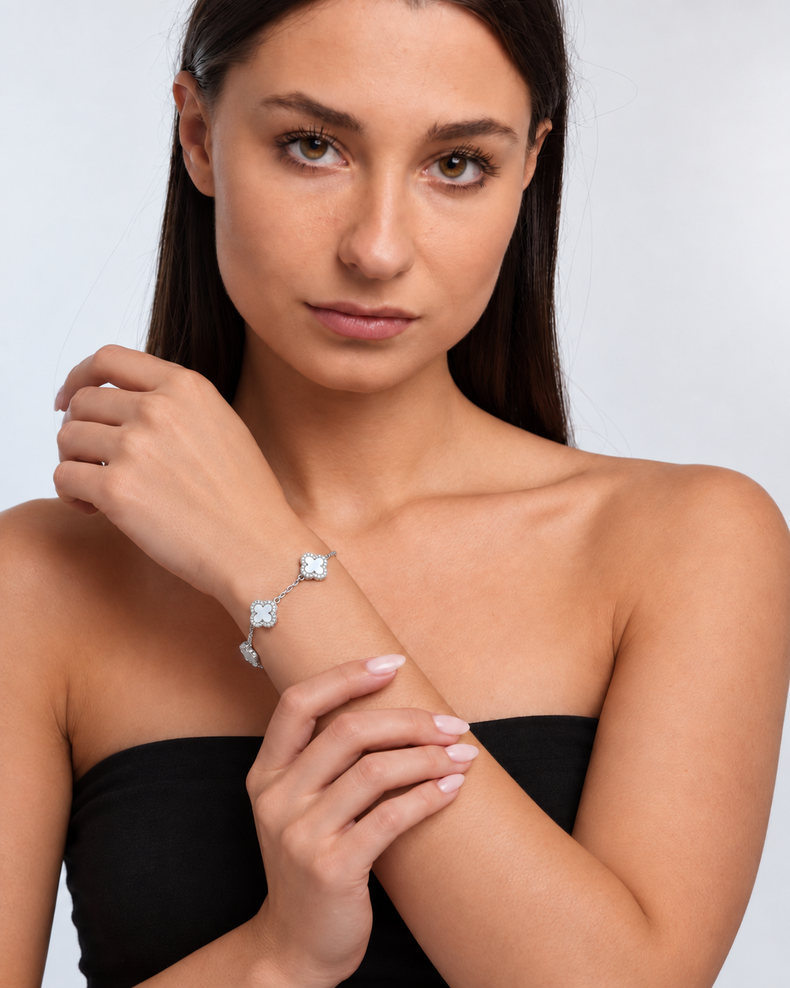 Clover bracelet with four white pearl-effect stations and clear stone borders in a silver finish worn around the model's wrist.