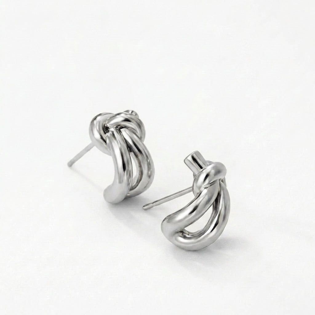Silver knot huggie earrings on a model's ear