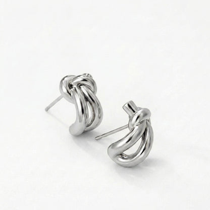 Silver knot huggie earrings on a model's ear