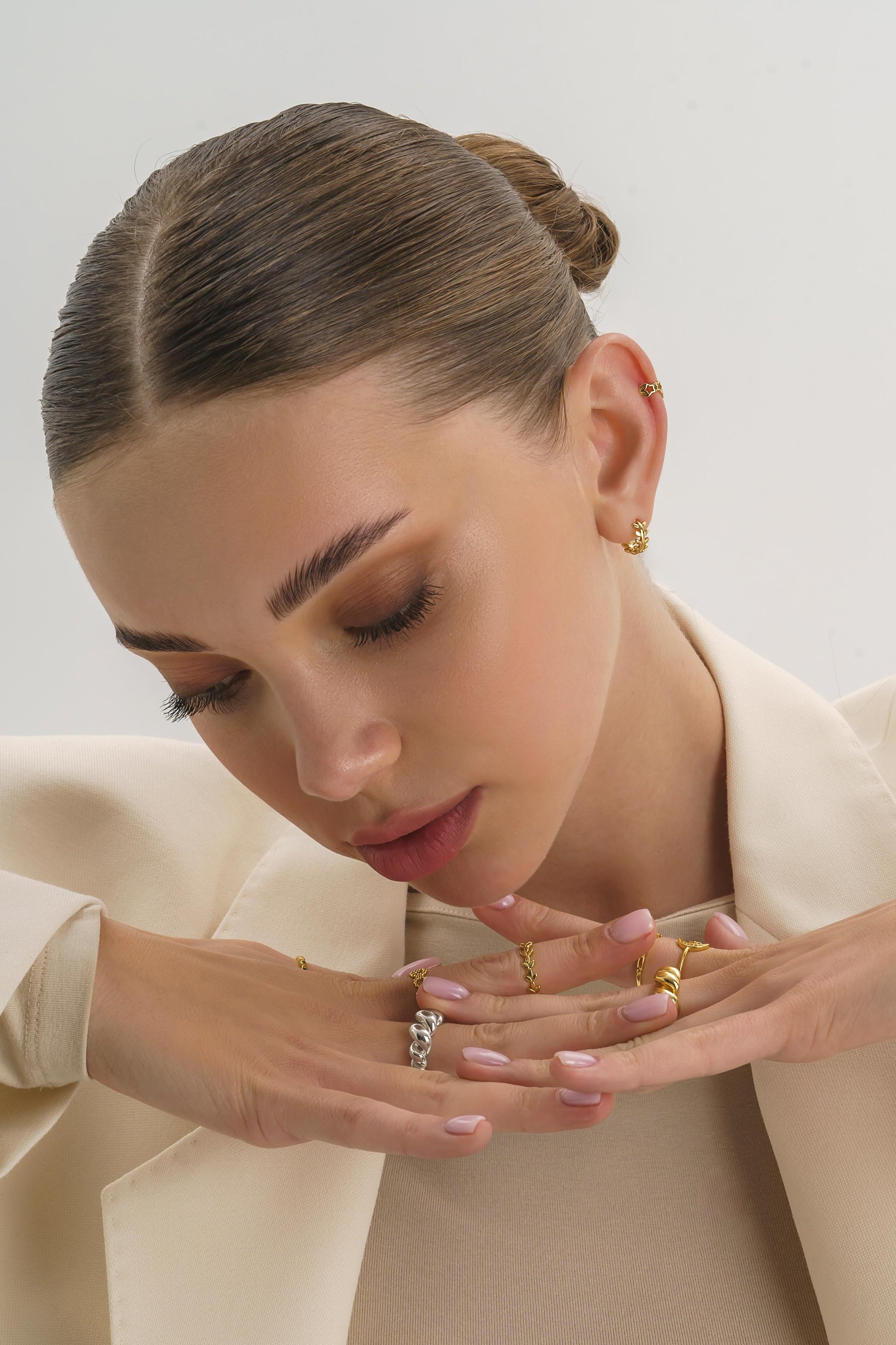 Tiny gold huggie hoops styled on a model's ear, close-fitting design
