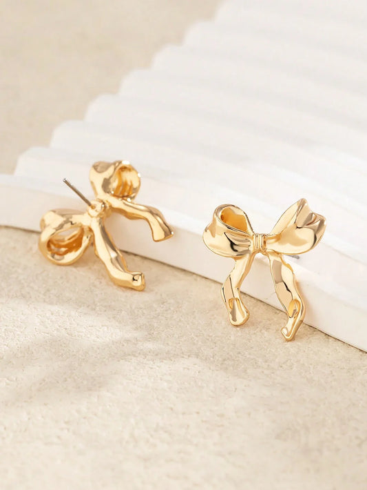 Close-up of gold ribbon bow earring — refined detail