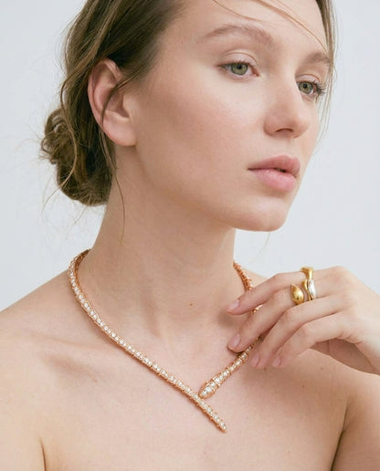 Close-up of gold snake necklace with round-cut white crystals