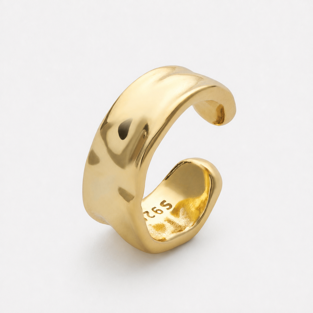 Gold-coloured open ear cuff photographed alone showing its curved polished band