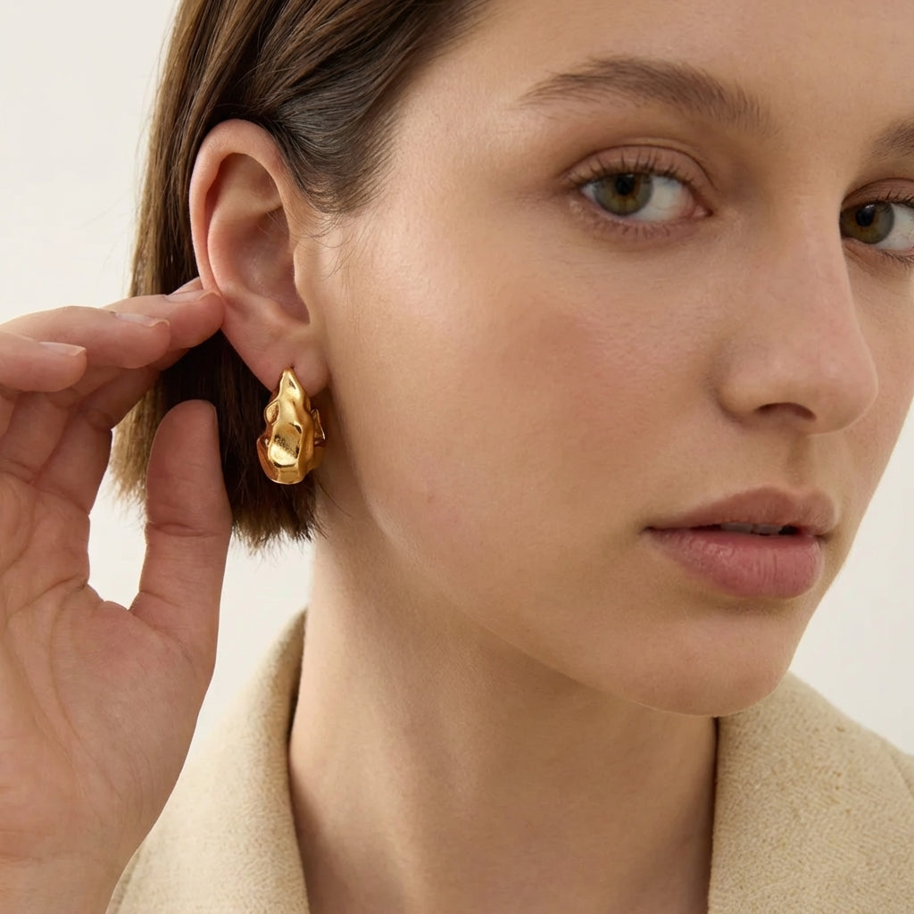 Gold molten-form drop earrings – flat lay