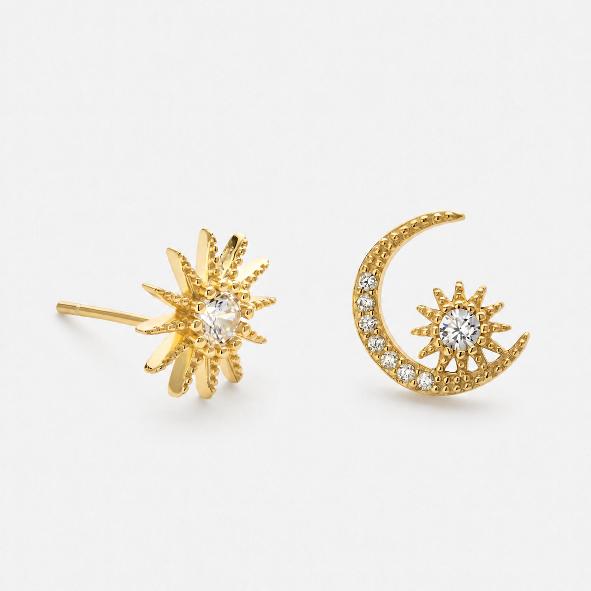 Gold-coloured starburst and crescent moon stud pair with clear stone accents photographed alone