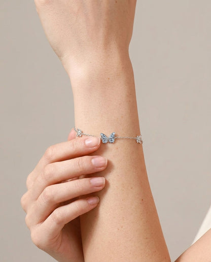 Glow-in-the-dark butterfly bracelet on wrist, hand-set enamel charm