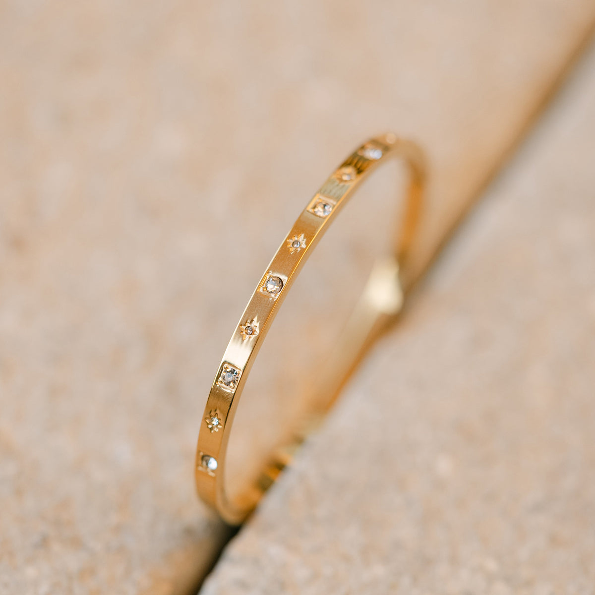 Gold bangle bracelet with sparkling star-set crystals