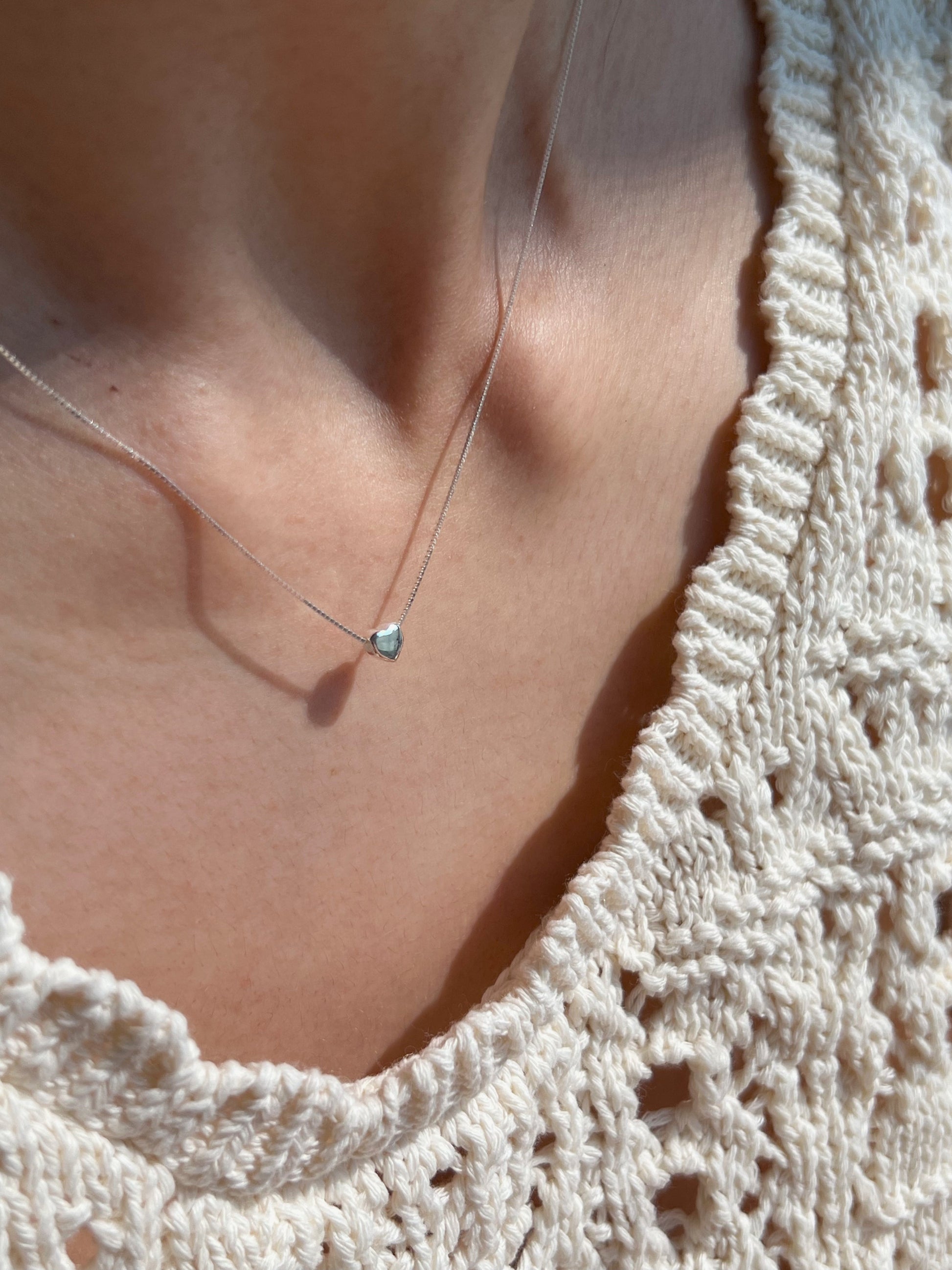 Petite heart necklace styled on a model's neckline