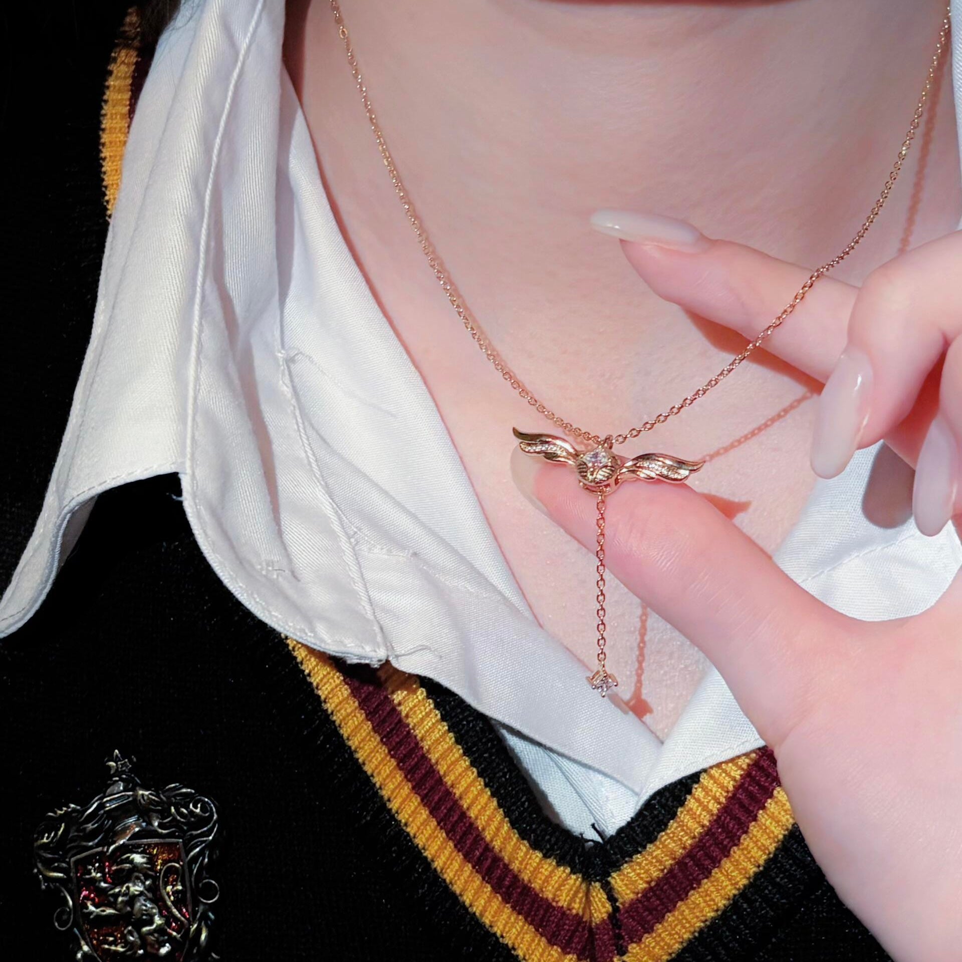 Gold-plated lariat necklace on neutral background, winged crystal pendant