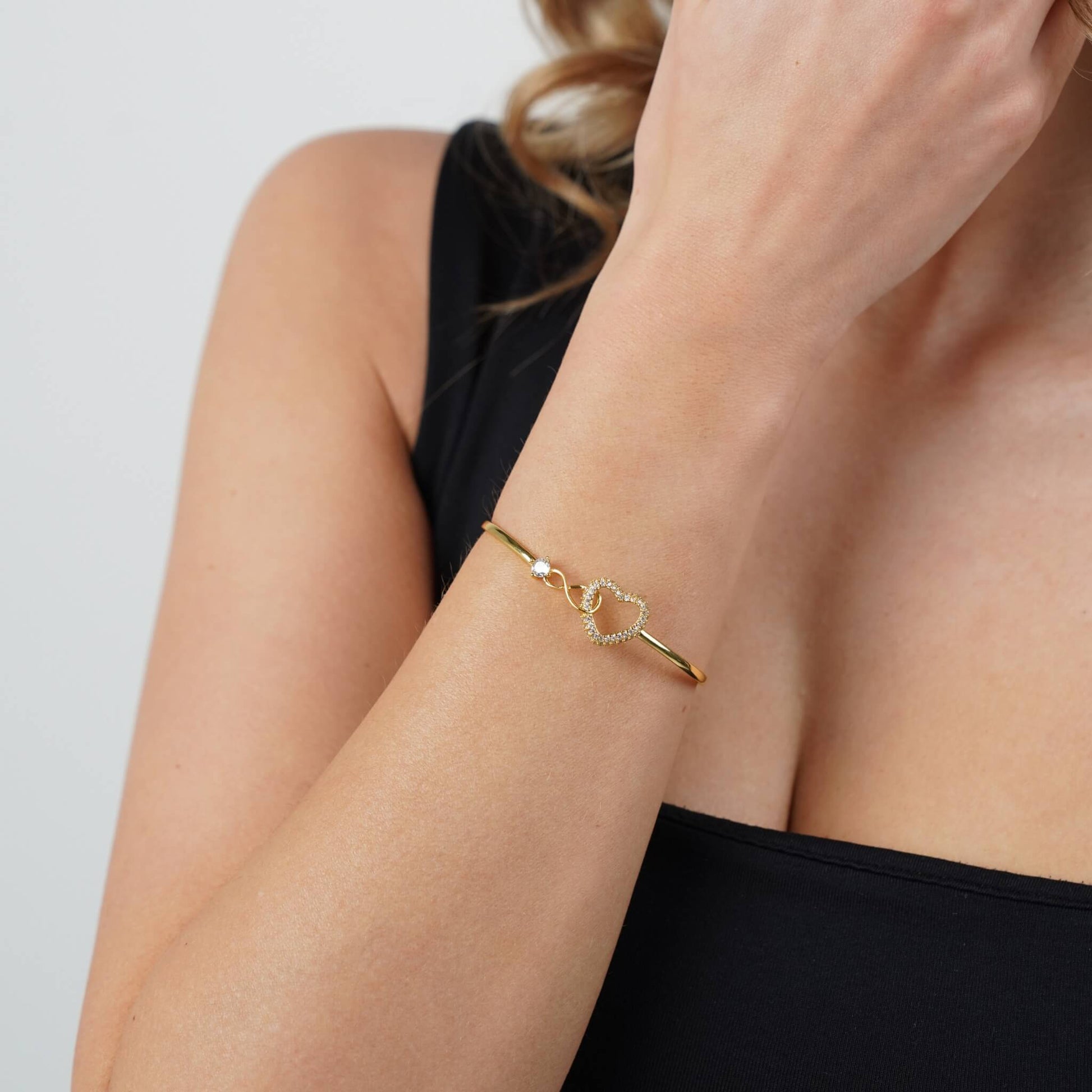 Adjustable infinity heart bracelet on a model's wrist, gold finish