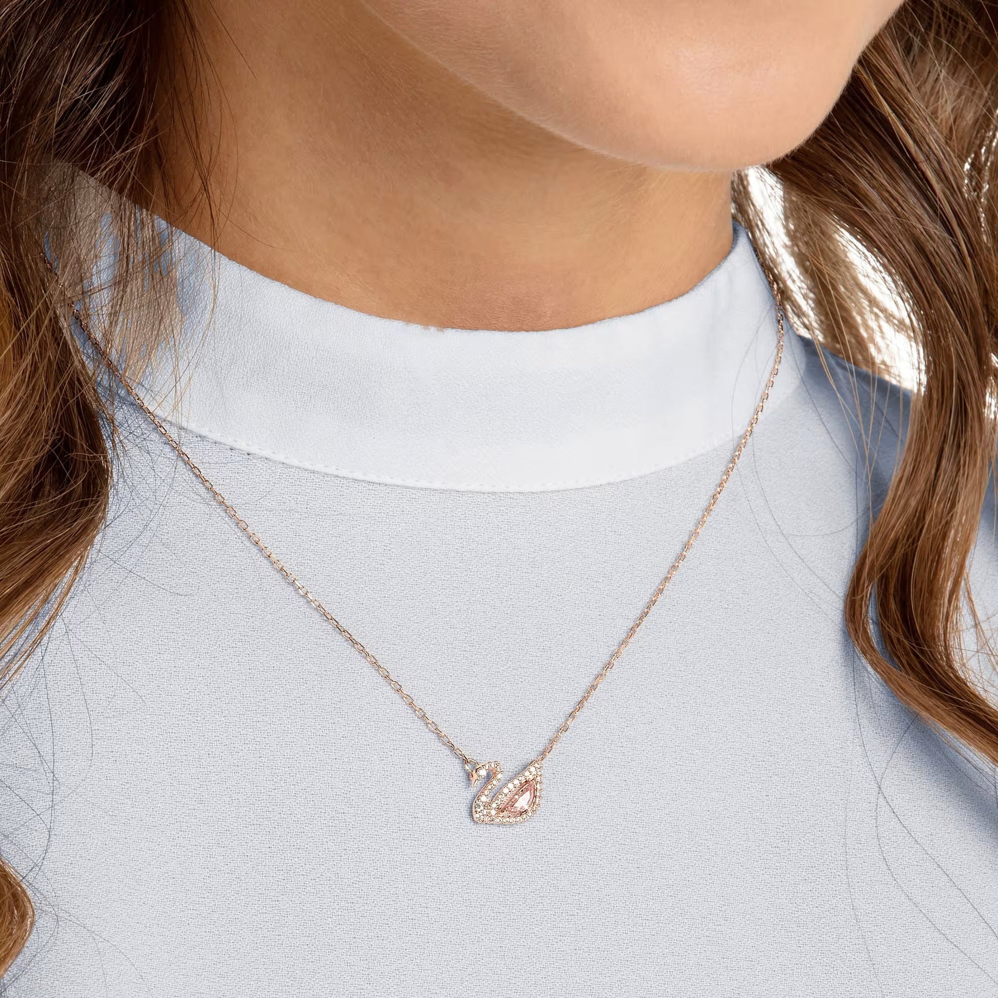 Rose gold swan necklace styled on a model's neckline