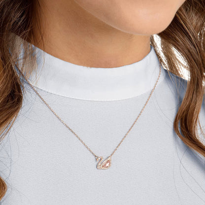Rose gold swan necklace styled on a model's neckline