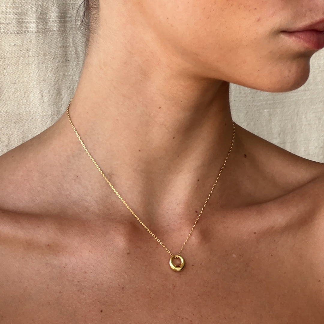 Close-up of tapered gold circle pendant detail