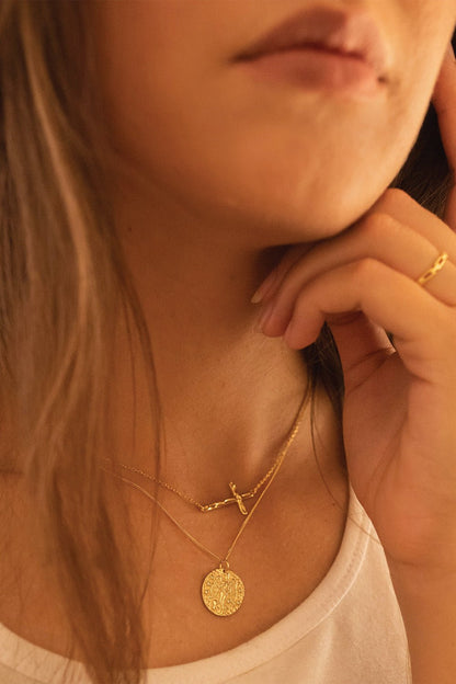 Close-up of dainty gold cross pendant detail