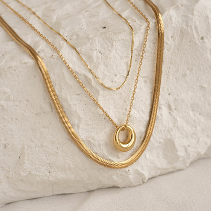 Gold circle necklace layered with other delicate gold chains