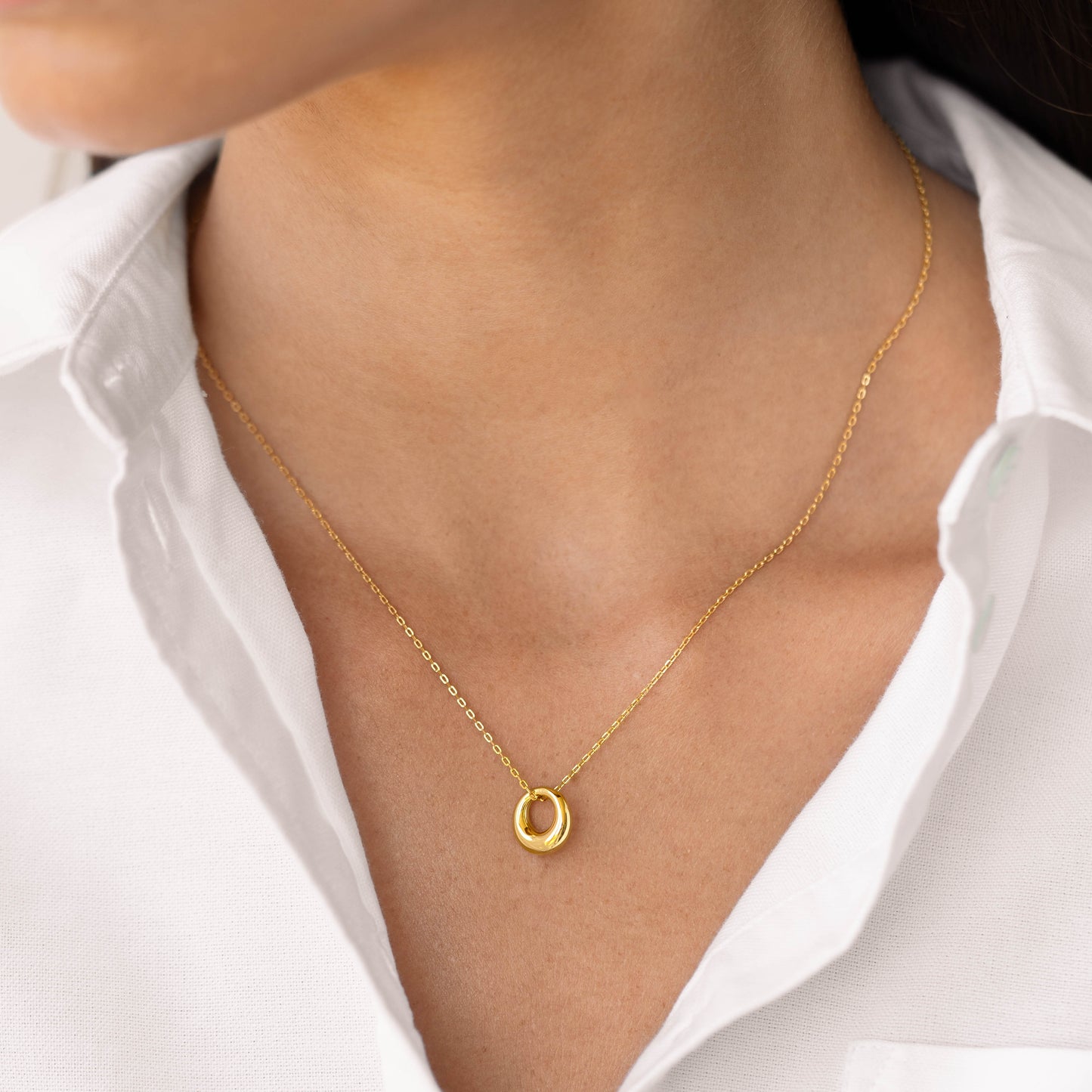 Timeless gold circle pendant necklace on a model's neckline