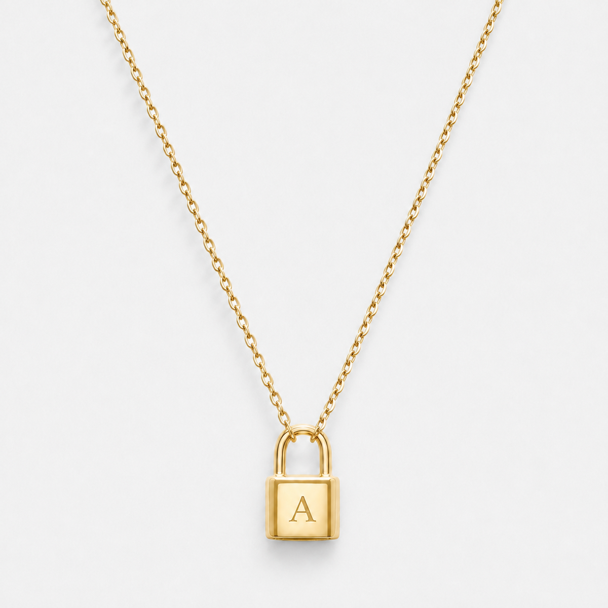 Padlock pendant necklace engraved with initial A in a gold finish on a neutral off-white background.