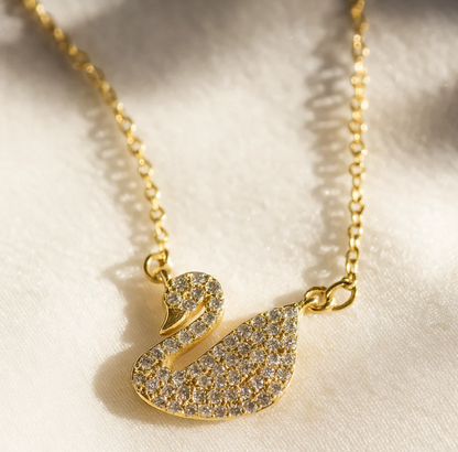 Geneviève gold swan necklace flat lay — 18K gold-plated brass pendant