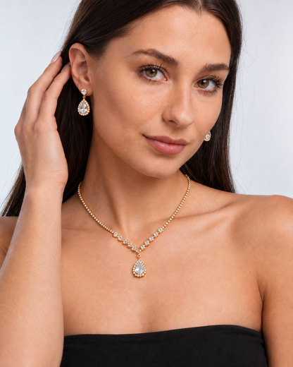 Crystal Teardrop Necklace & Earring Set in Gold / Clear, worn by a model in a three-quarter portrait - Ravyena