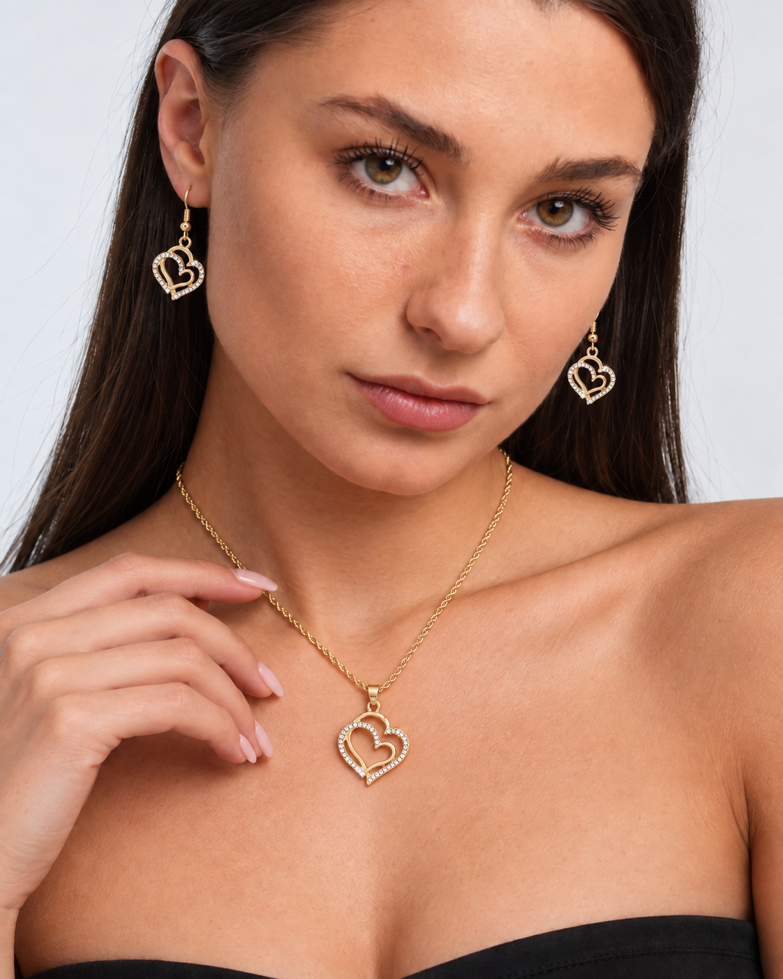 Double Heart Crystal Necklace & Earring Set in Gold, worn by a model in a close-up - Ravyena