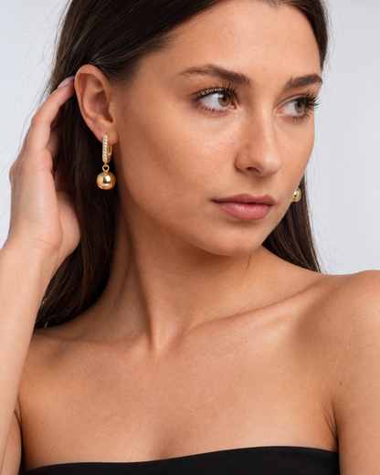 Gold-Tone Crystal Ball Drop Hoop Earrings in Gold, worn by a model in a three-quarter portrait - Ravyena