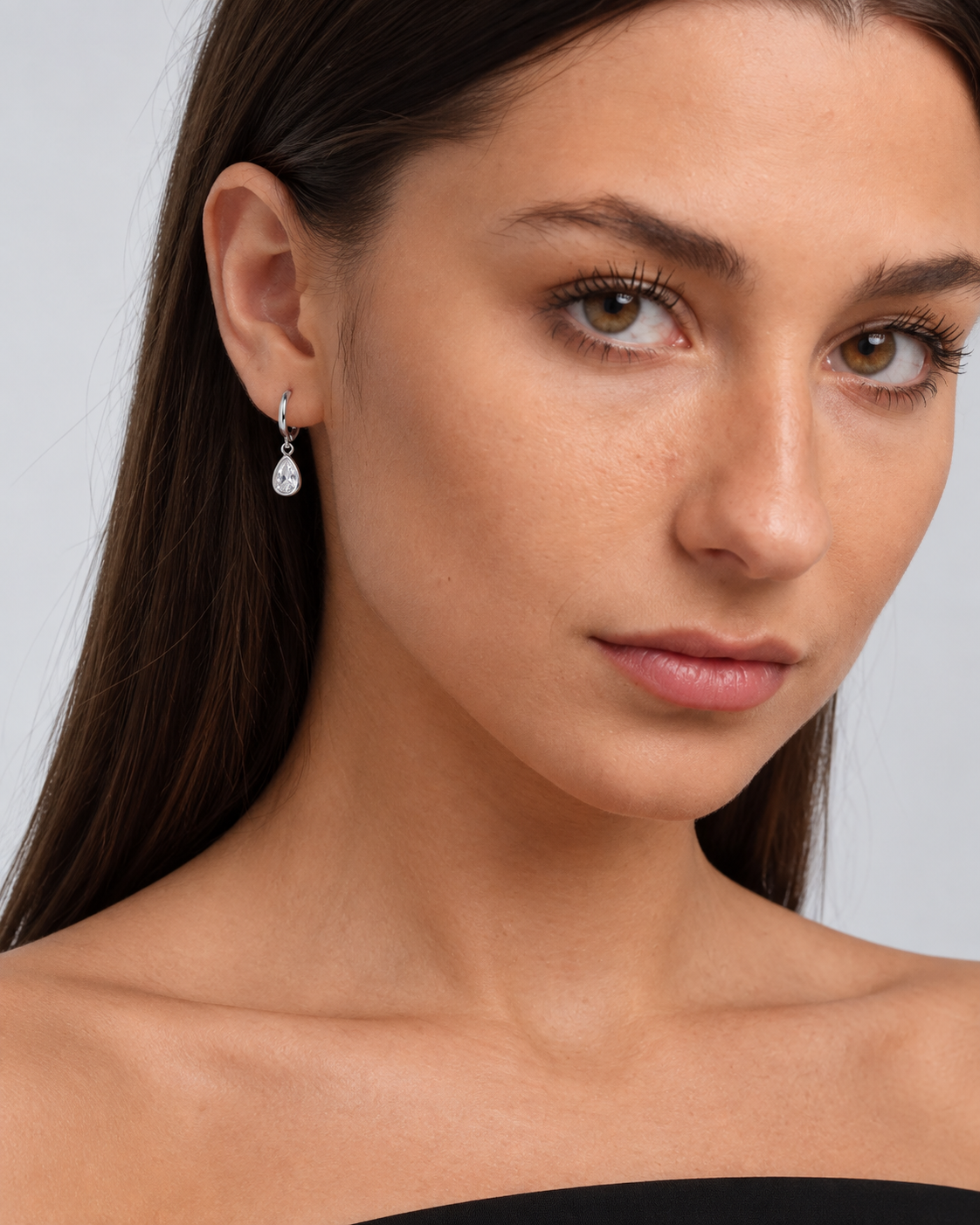 Dainty Teardrop Crystal Hoop Earrings in Silver, worn by a model in a close-up - Ravyena