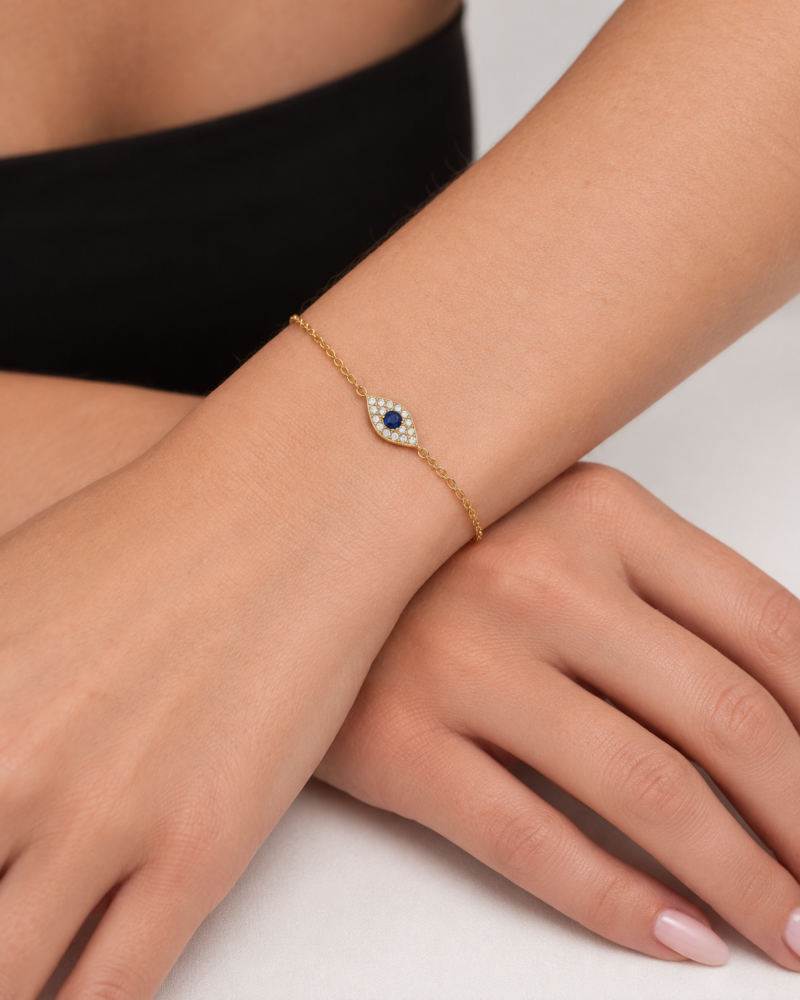 Pavé evil eye chain bracelet in 18K gold vermeil with a blue centre stone, worn in close-up on the wrist