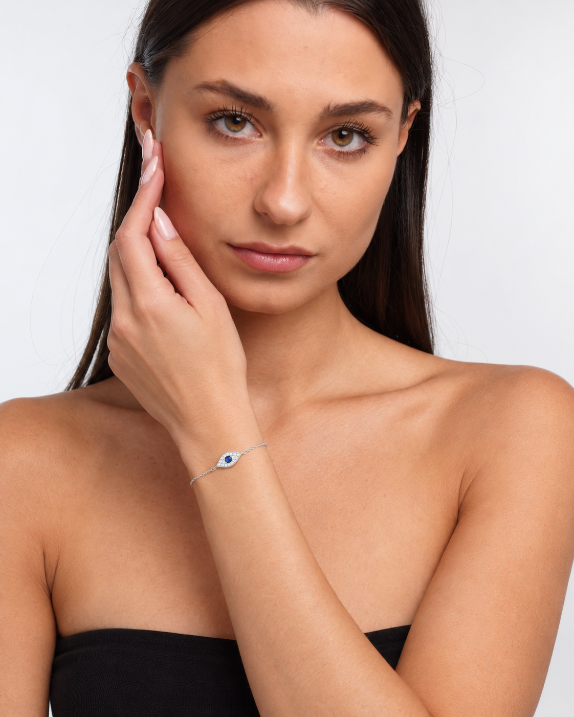 Pavé evil eye chain bracelet in sterling silver with a blue centre stone, worn in portrait with raised wrist