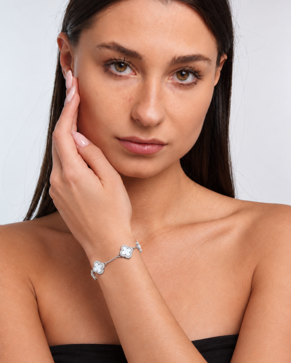 Clover bracelet with four white pearl-effect stations and clear stone borders in a silver finish worn around the model's wrist.