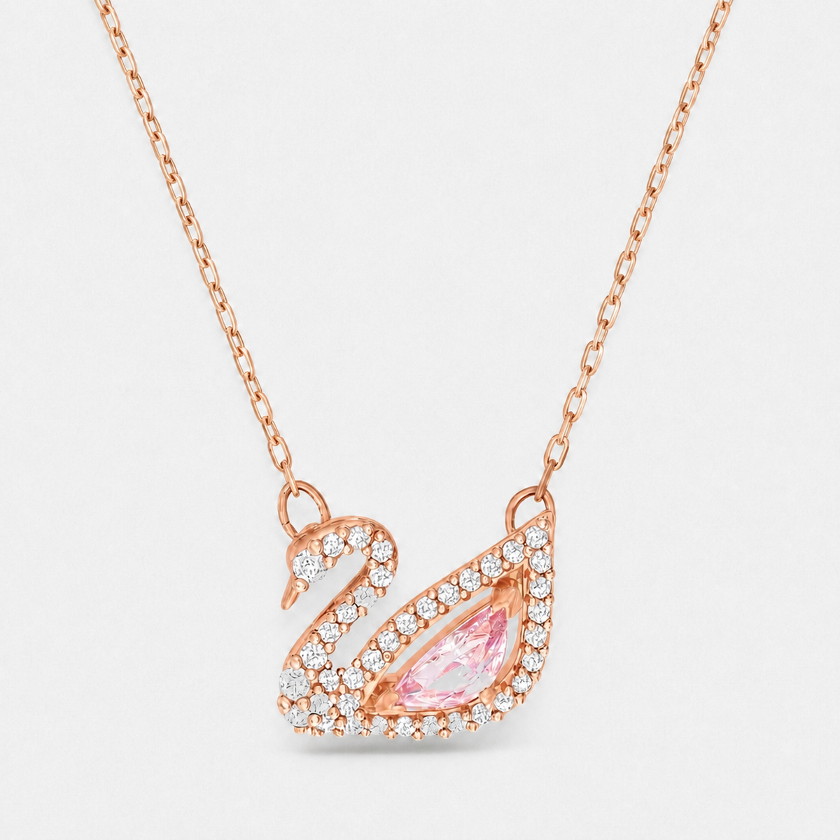 Swan pendant necklace with pink pear-shaped centre stone and clear stone outline in a rose gold finish on a neutral off-white background.
