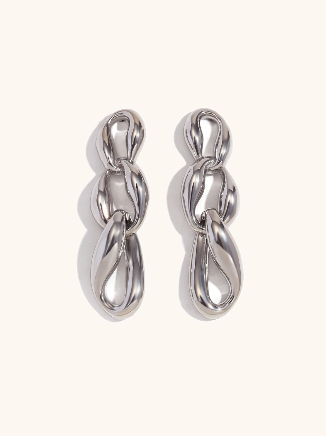 Gold chain drop earrings on neutral background — full length view
