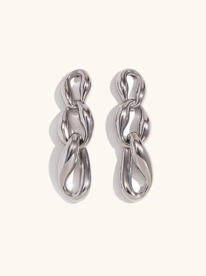 Gold chain drop earrings on neutral background — full length view