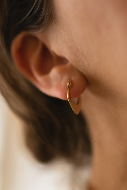 Gold geometric hoops styled on a model's ear