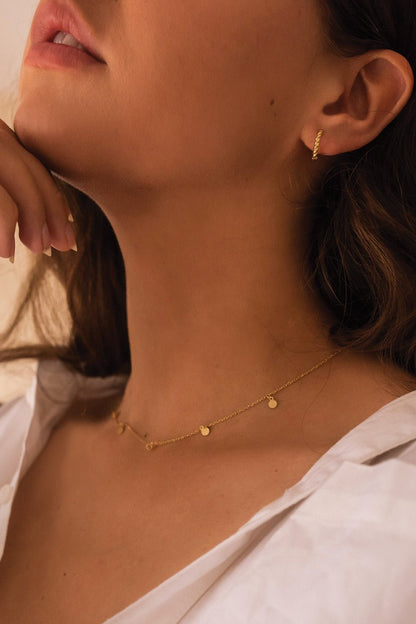 Close-up of small gold thin hoop earring detail