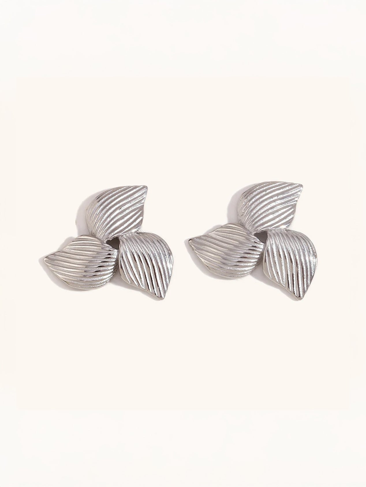 Gold floral earrings on neutral background